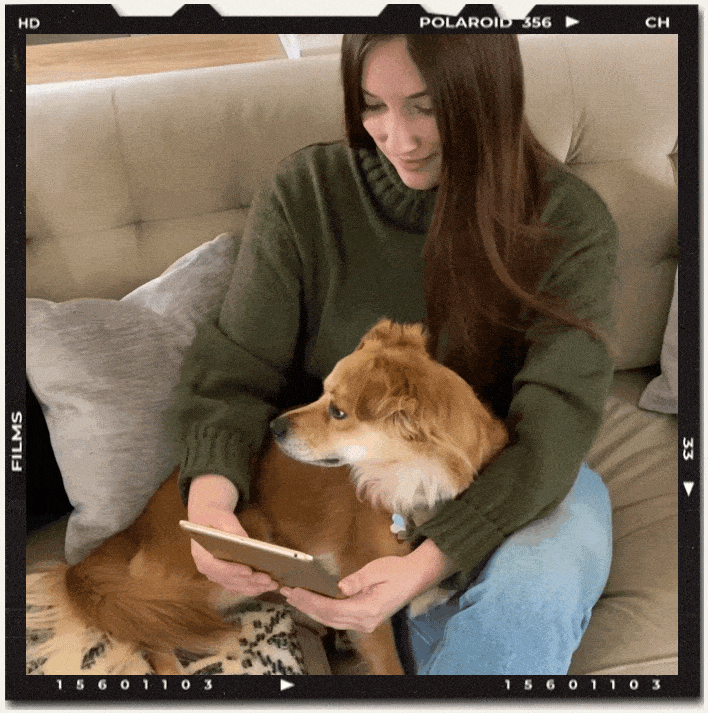 Girl sitting on the couch working on her ipad with her dog