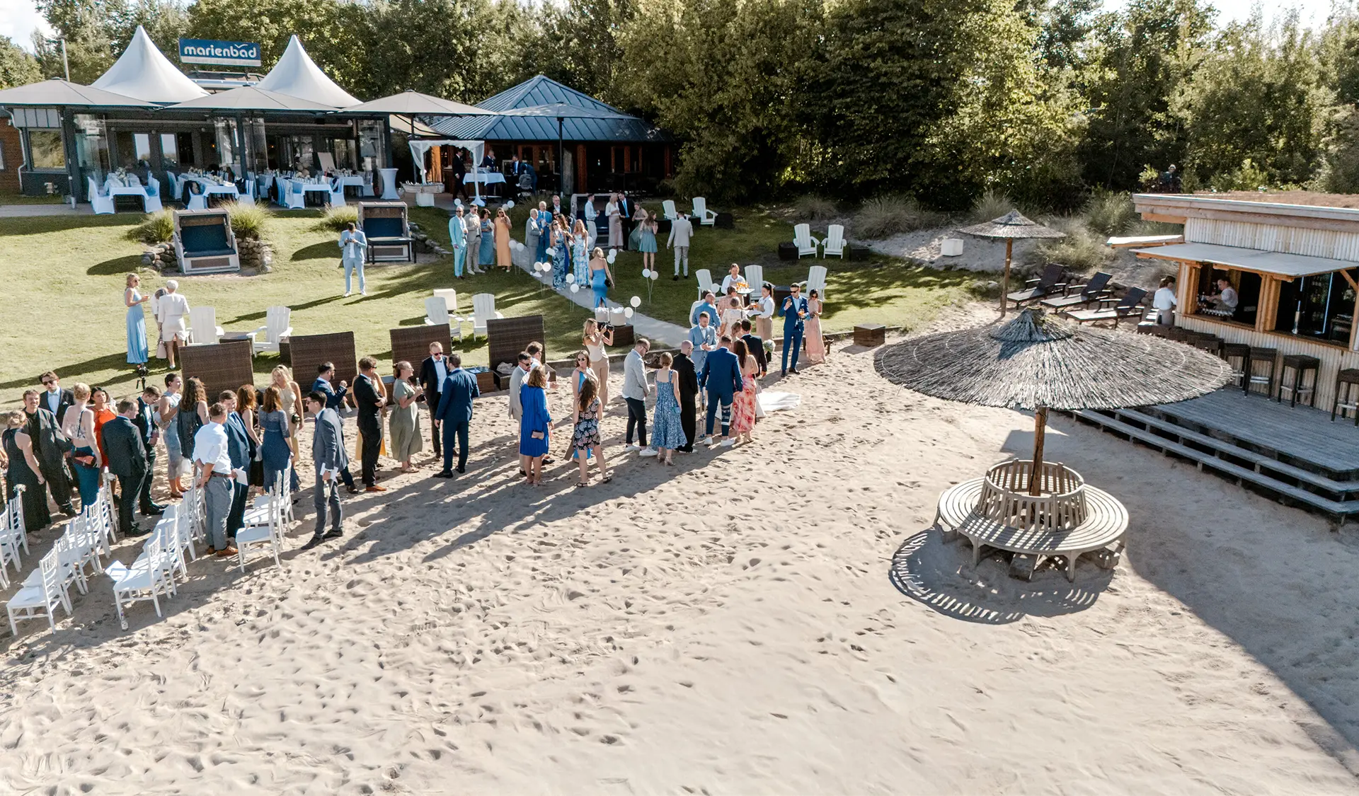 Drohnenaufnahmen Hochzeit im Strandrestaurant Marienbad – Gäste beim Empfang am Strand in Schleswig-Holstein.