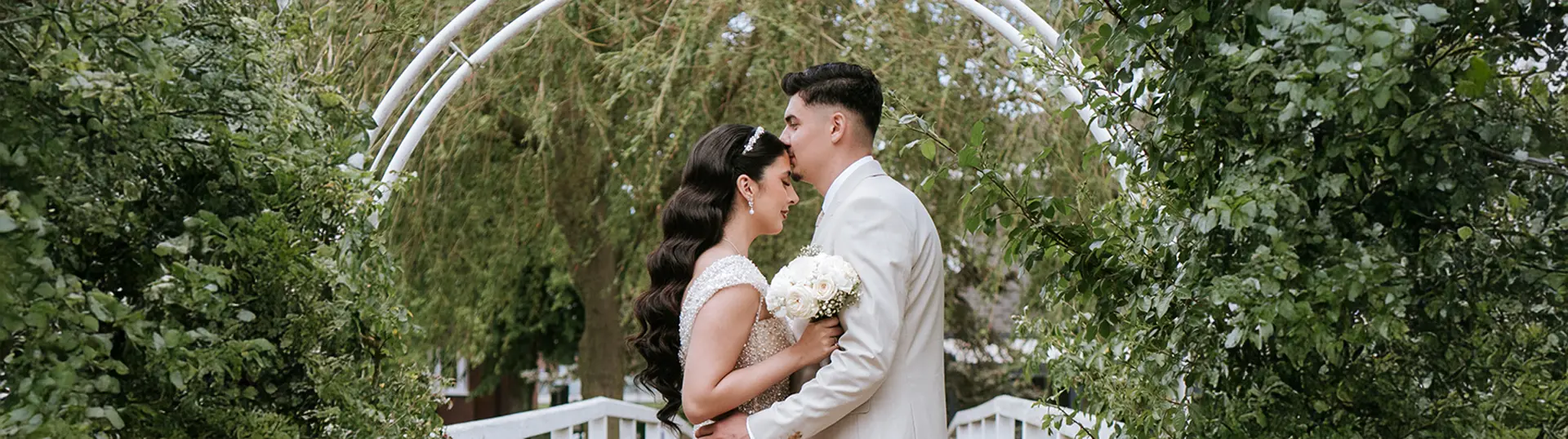 Braut und Bräutigam umarmt auf der Holzbrücke im Rosarium Park, Stirnkuss zwischen grünen Bögen; natürliche hochzeitsfotografie und hochzeitsfotograf für zwei1