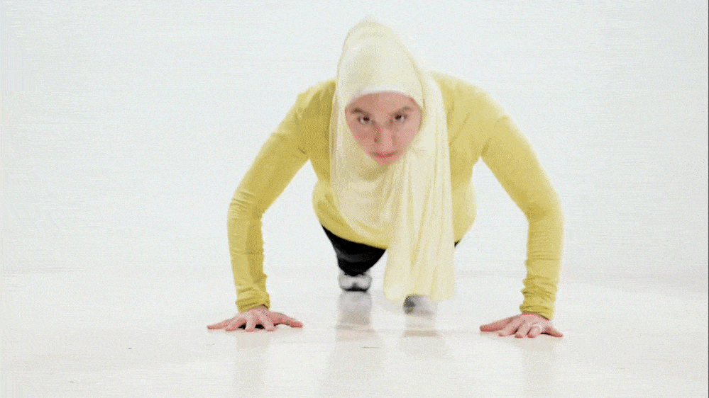 Fitness hijabi coach Hanan going through her workout routine with dumbells while wearing a yellow shirt