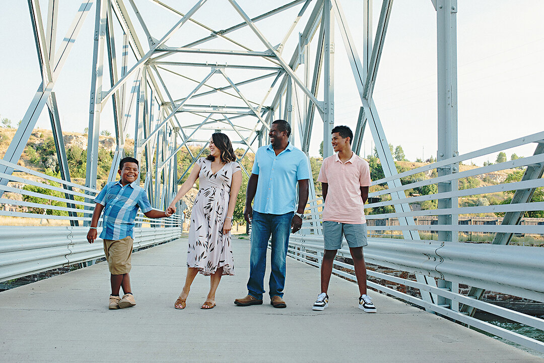 a family of 4 on a bridge wearing beautiful pastel colors