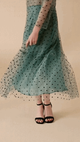 Video of woman spinning in a polka dot teal dress