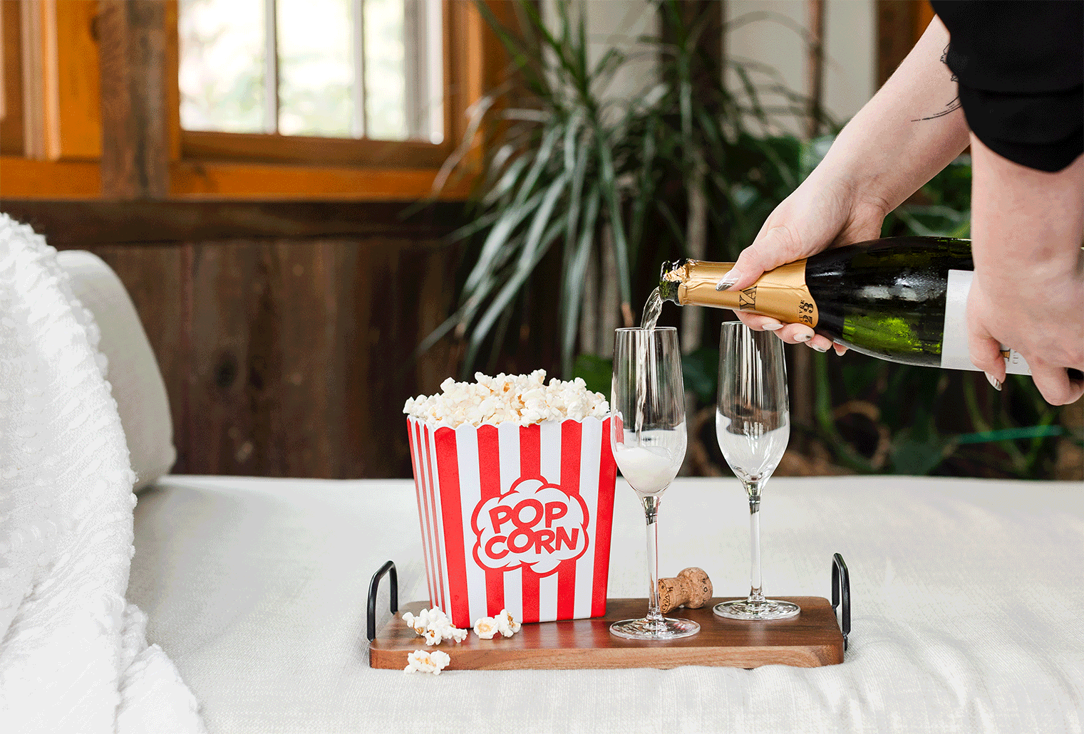 a female filmmaker pours champagne next to a bucket of popcorn