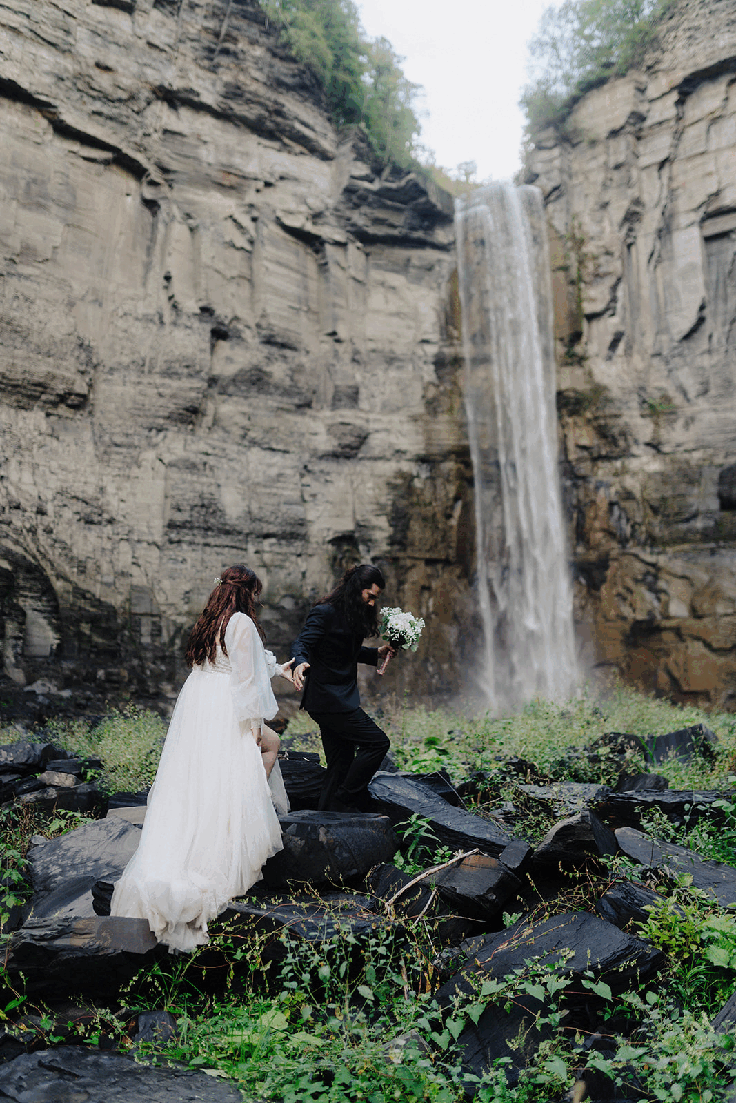 Bride and groom walking up steps in fron of Taughannock Falls, NY