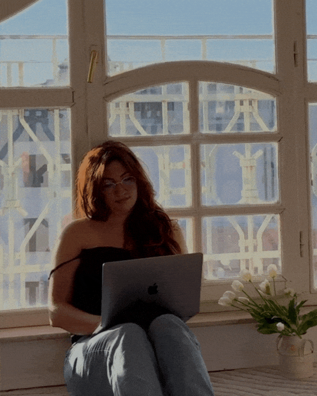 Video of a girl working on a laptop and then looking into the camera and smiling