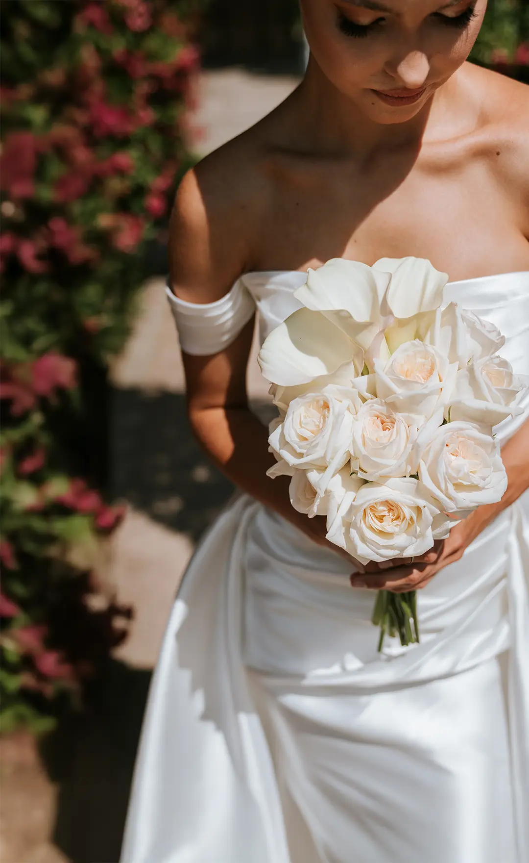 Nahaufnahme einer Braut im schulterfreien Seidenkleid, die im Sonnenlicht einen weißen Rosen- und Calla-Strauß hält; edler Look für fine art hochzeitsfotografie und künstlerische hochzeitsfotos