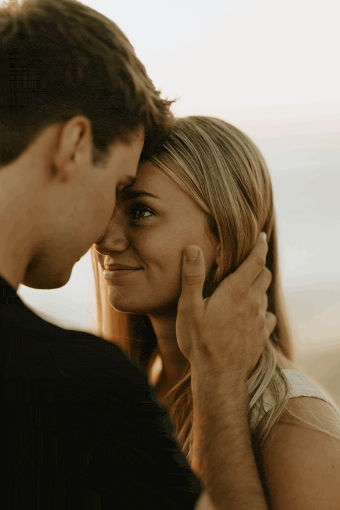 A GIF of a man caressing his fiancée's cheek while she smiles and closes her eyes.