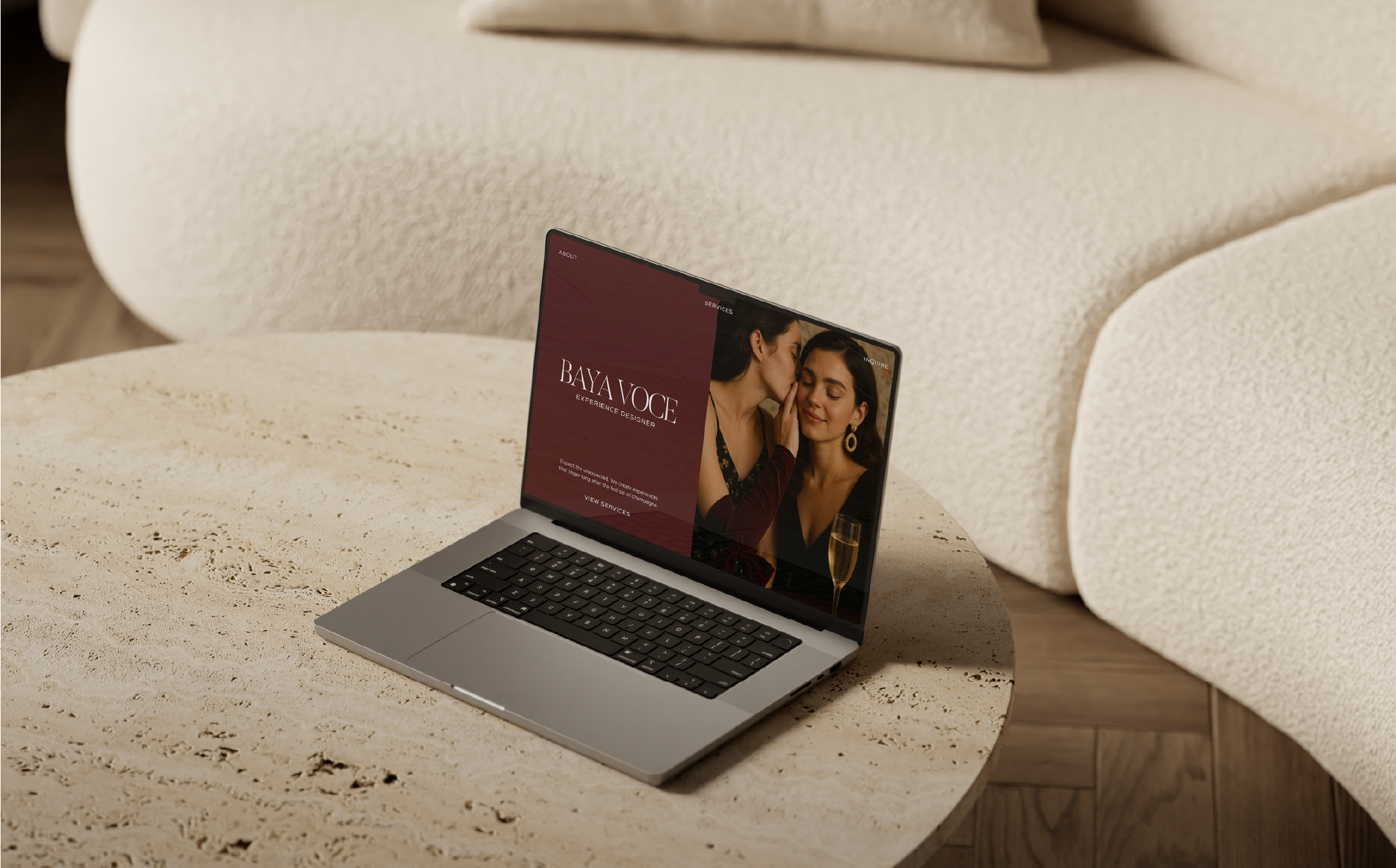 Laptop screen featuring the Baya Voce homepage with luxury branding visuals and elegant typography, placed on a textured travertine table.