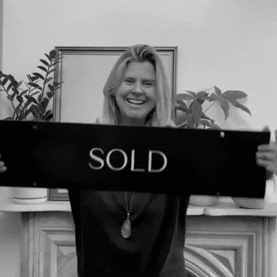Amy Ahlers hold a sold sign