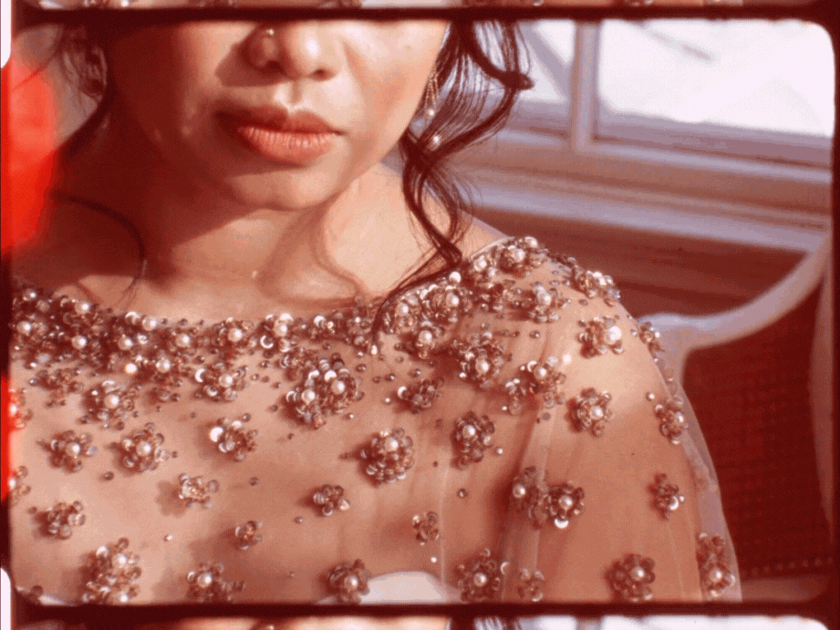 Close-up frame from a 16mm wedding film featuring a bride in a beaded gown, bathed in soft vintage tones — captured by an analog wedding videographer.