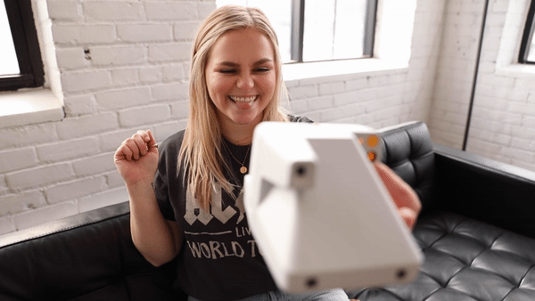 Gif of a person taking a Polaroid photo with flash