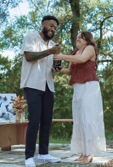 newly engaged couple pops champagne in front of family and friends