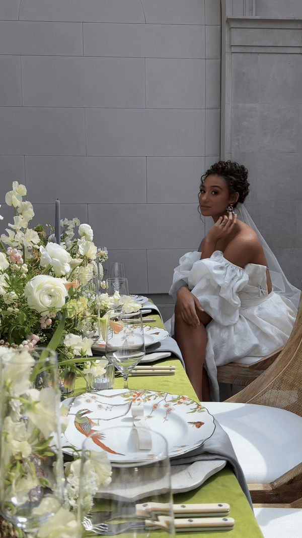A bride at a table adorned with white and green flowers, capturing a moment from a Columbus wedding.