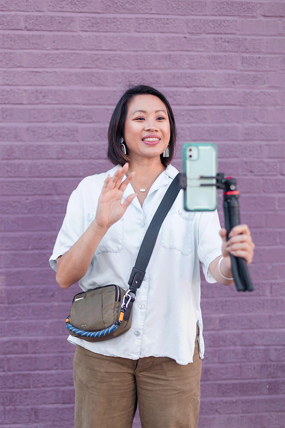 gif of a woman holding a phone with a tripod and waving at it