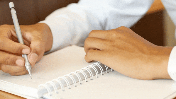 Man handwriting with a pen in an open notebook