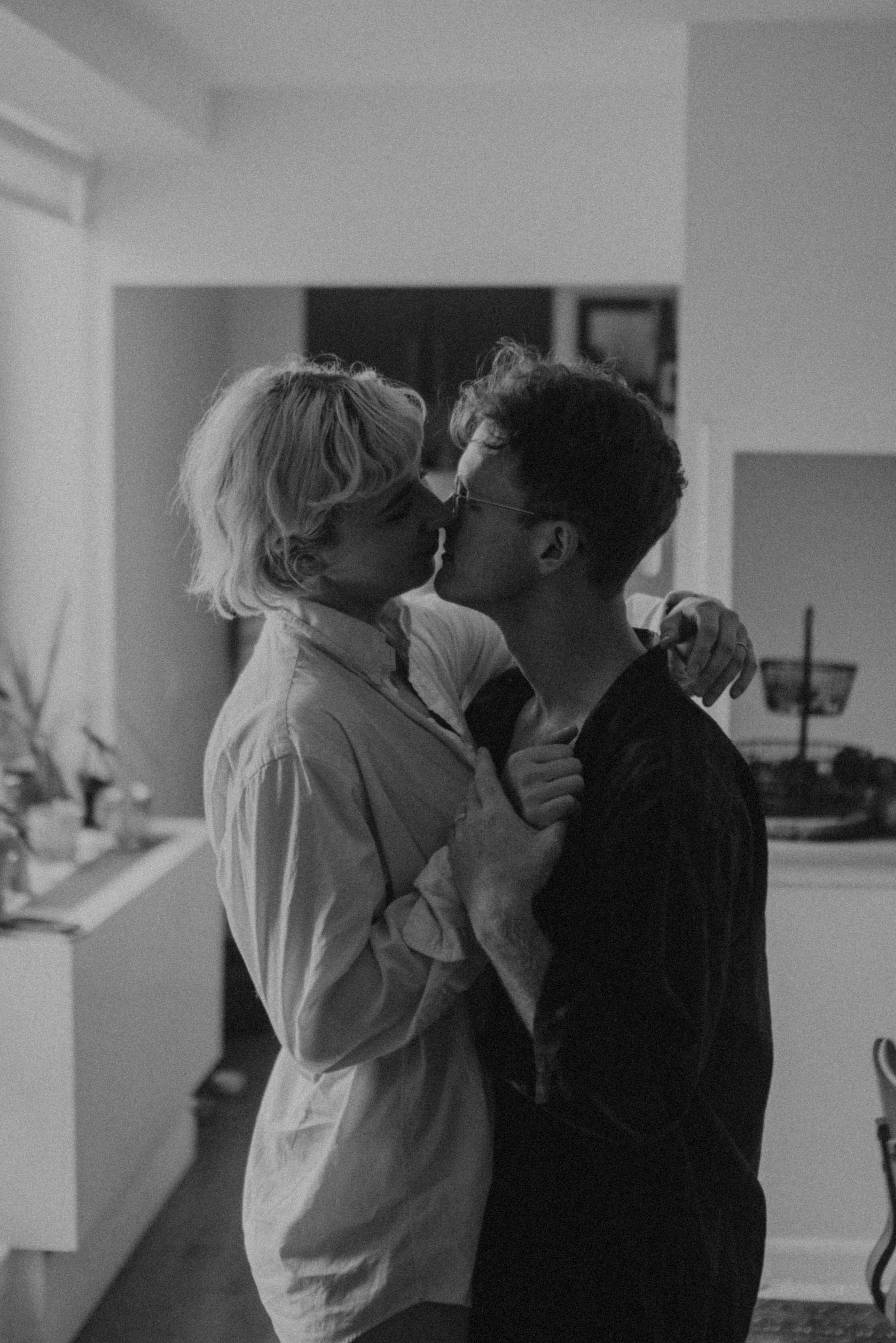 Couple sharing a tender kiss while dancing in their living room, black and white photo