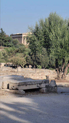 Cultural travel specialist Stephanie Dosch walking in Athens, Greece's ancient Agora, with olive trees and an ancient temple behind ©Stephanie Dosch | theViatrix Custom Itinerary Planning