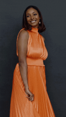 A woman in an orange dress beams with happiness, showcasing the essence of a destination wedding planner's creativity and charm.