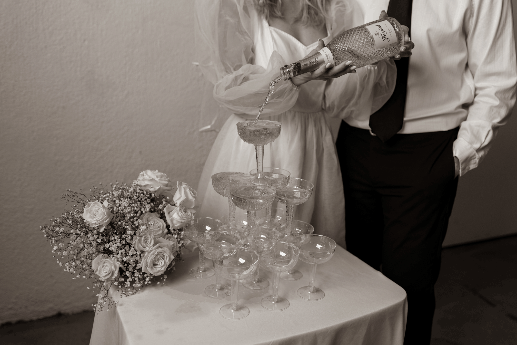 close up of bride pouring champagne into champagne tower