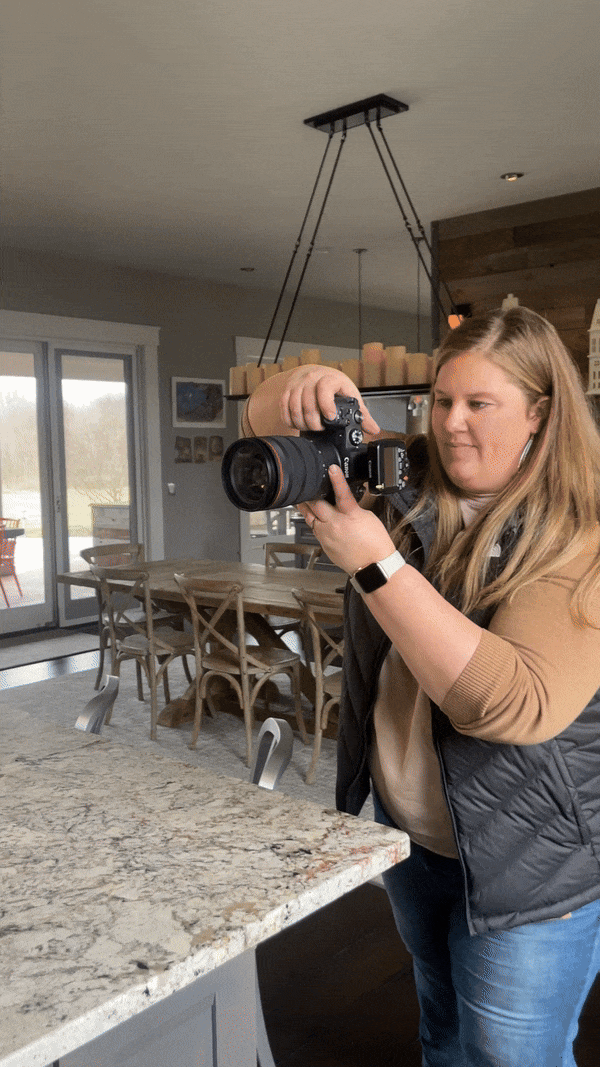 A dynamic behind-the-scenes shot of Meg Williamson capturing the beauty of a custom home. This image showcases her expertise and passion for architectural photography, highlighting her hands-on approach during a custom home shoot.