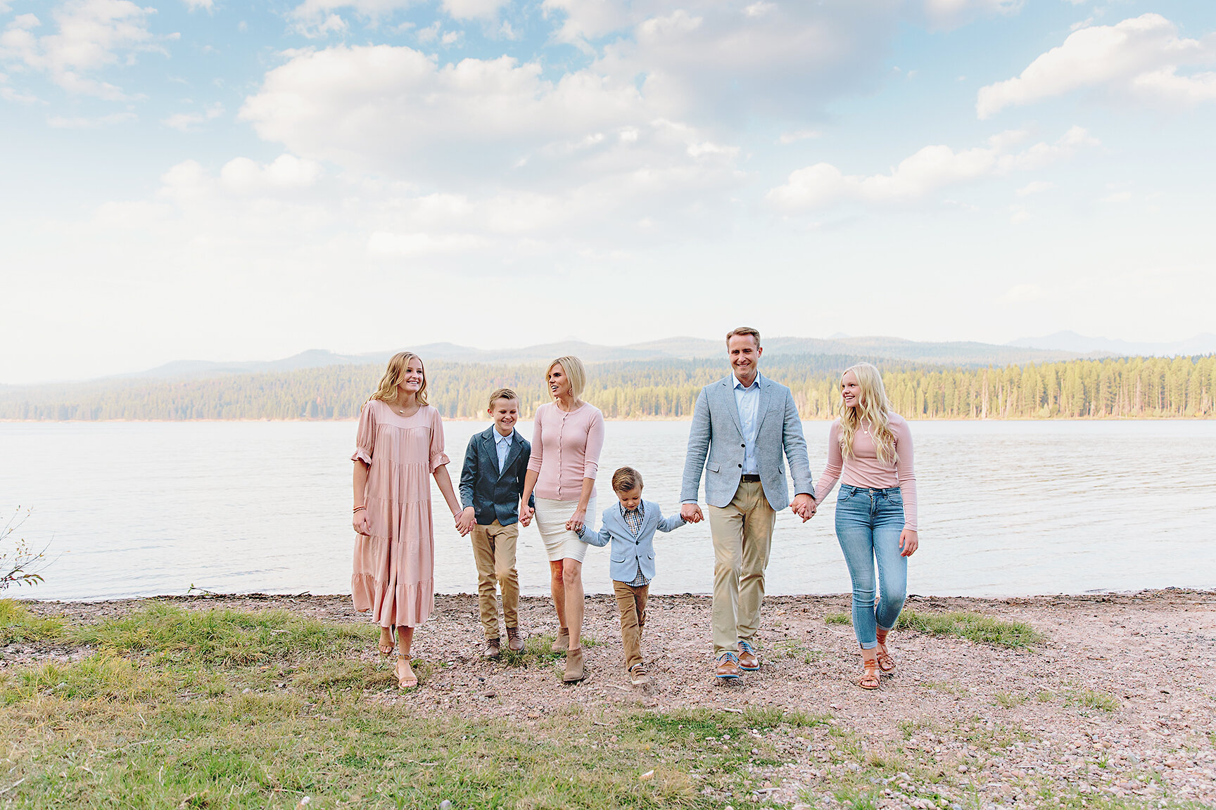 a family of six on a like wearing soft pastel colors with a dressy style