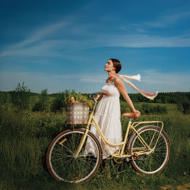 girl with bike with scarf blowing in wind in an Italian field