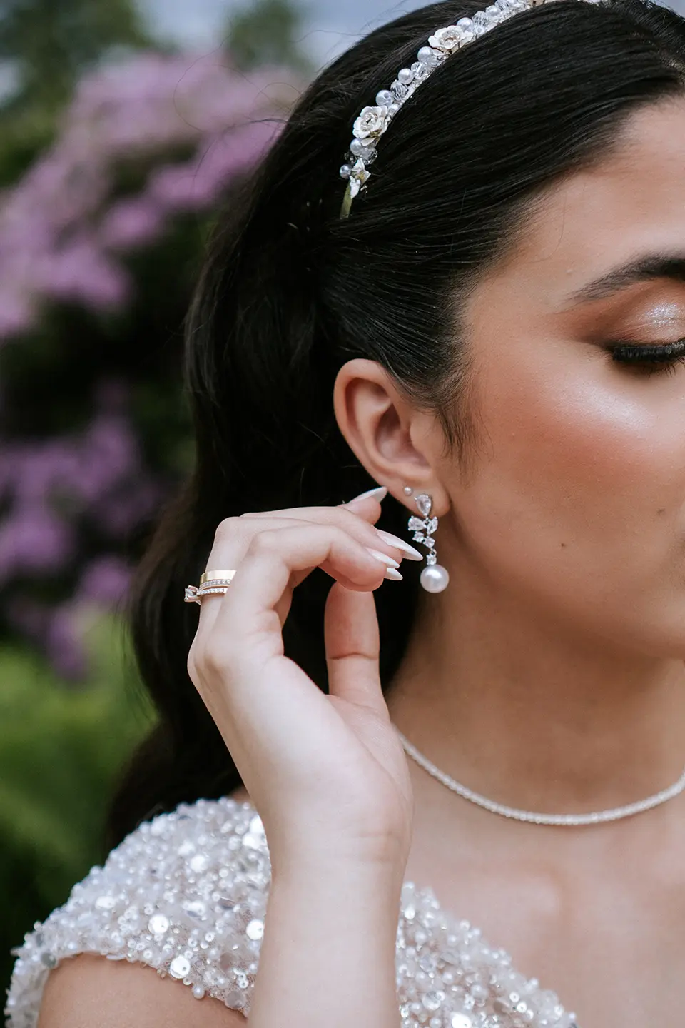 Nahaufnahme der Braut, die den Perlenohrring richtet; glitzerndes Diadem, sanftes Make-up und zarte Hauttöne im Garten, künstlerische hochzeitsfotos und fine art hochzeitsfotografie