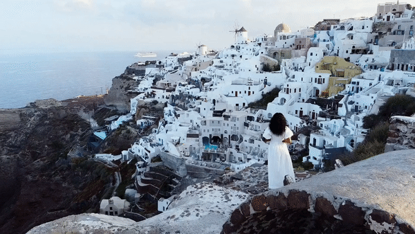 Video of woman in white dress overlooking Santorini