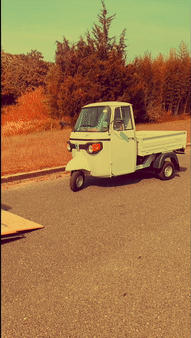 a moving picture of a piaggio ape being loaded into the back of a truck