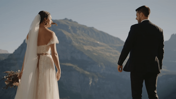 Brand and groom reaching to hold hands in front of mountain landscape