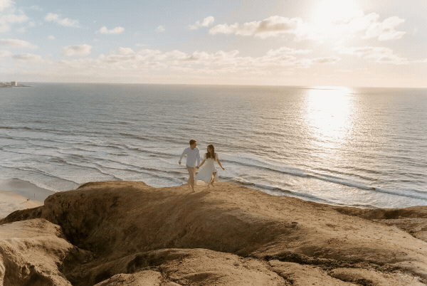 bride and groom walking on cliff
