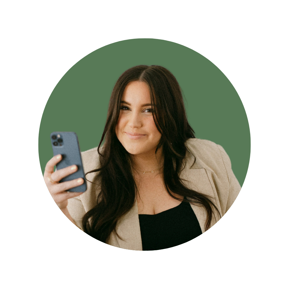 Jordan M., a Web Designer Library member, smiling while holding a phone, wearing a beige blazer over black top.