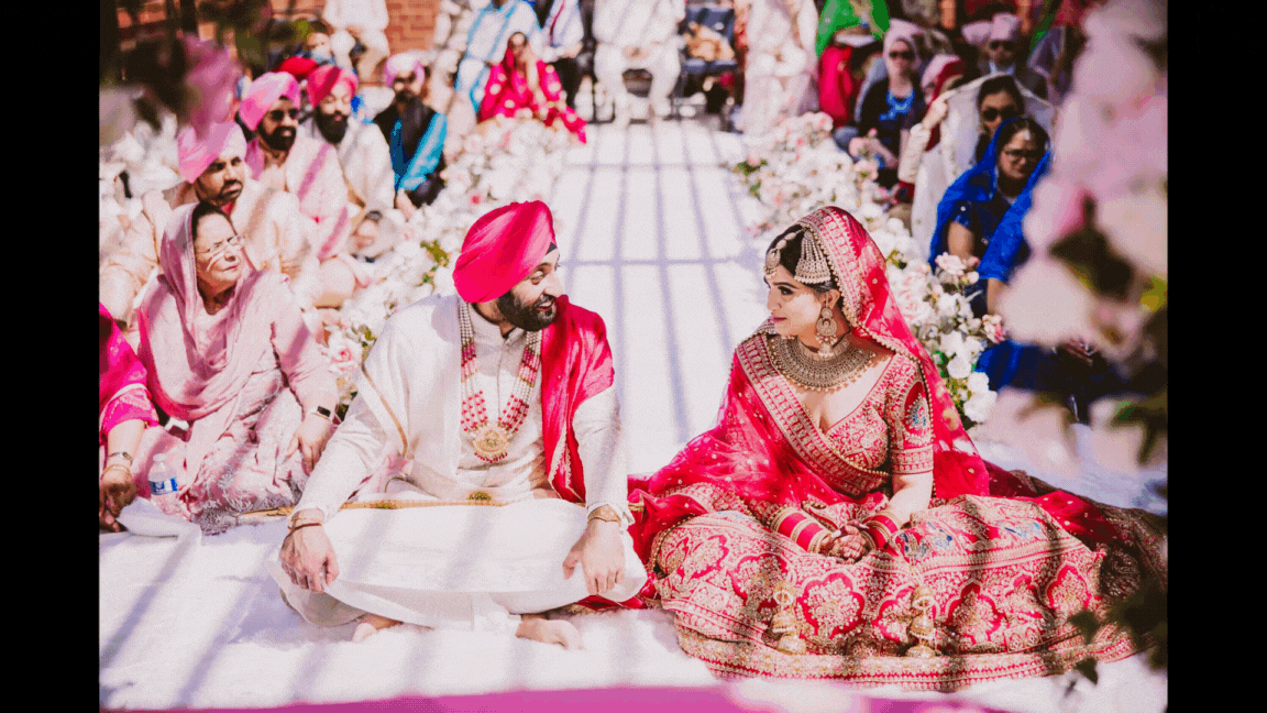 A gif of an indian bride and groom exchanging looks during their anand karaj wedding ceremony
