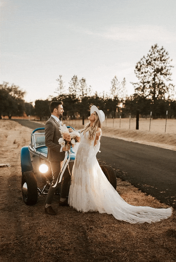 blue hour photo of bride and groom dancing on a road in front of a vintage car