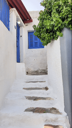 Gif of luxury travel expert Stephanie Dosch, aka theViatrix walking down stairs between whitewashed buildings with blue shutters in the Anafiotika district of Athens, Greece ©Stephanie Dosch | theViatrix Luxury Cultural Travel