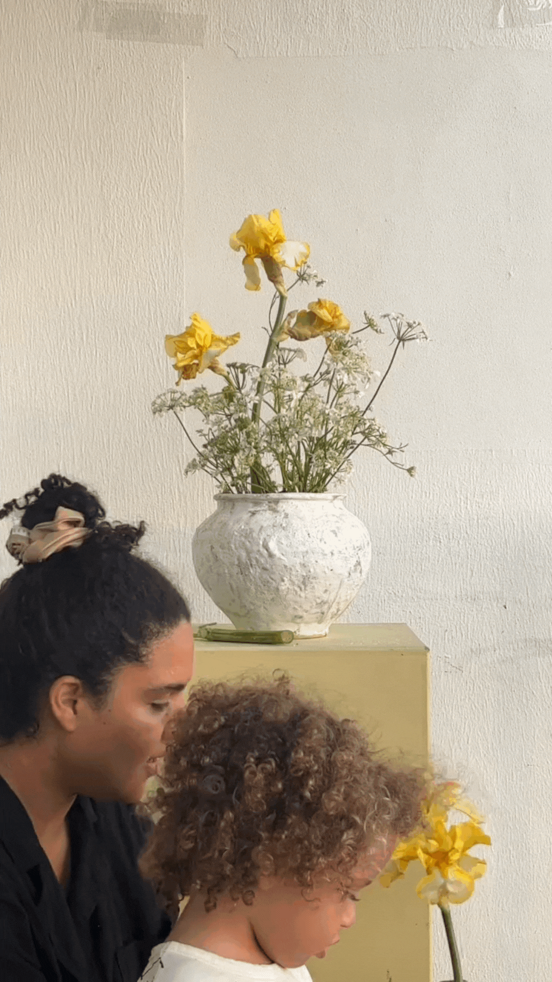 Kai pulls some flowers from a vase and hands them to his mom.