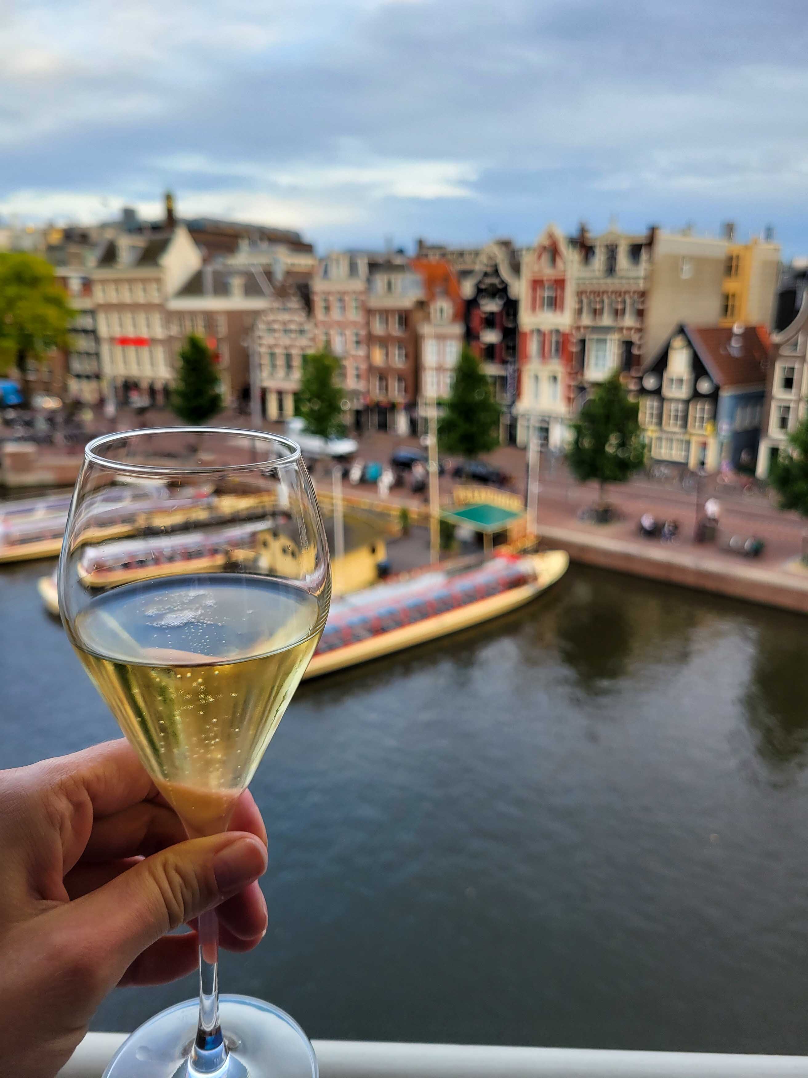 Glass of champagne with a view of an Amsterdam canal and canal houses in the background ©Stephanie Dosch