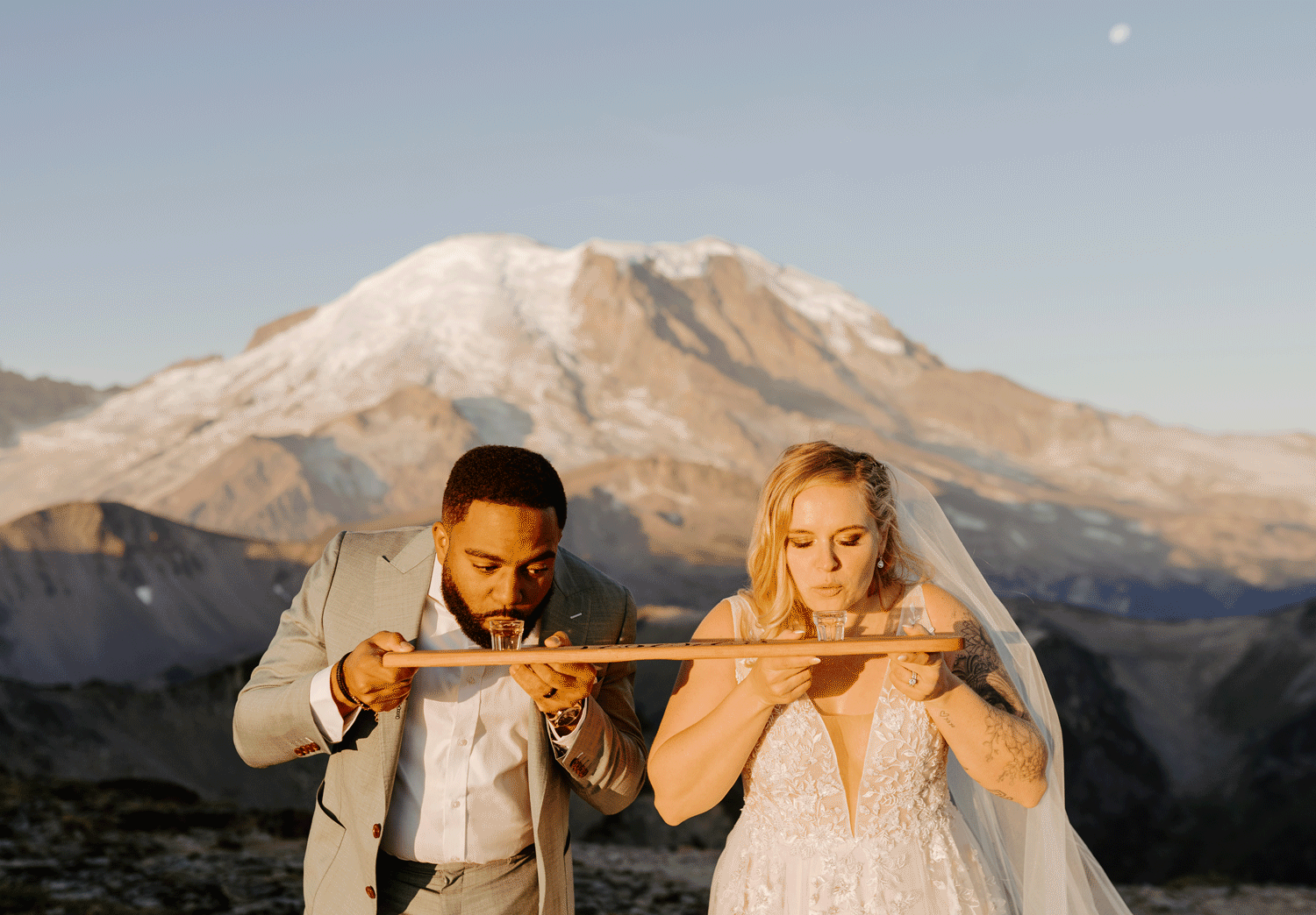 Bride and groom drinking shots in front of a mountain