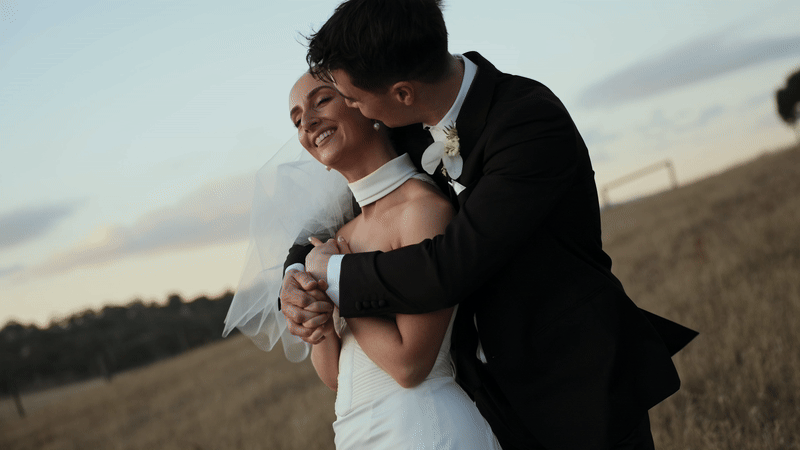 Bride draped in her veil, holding her boquet of white roses