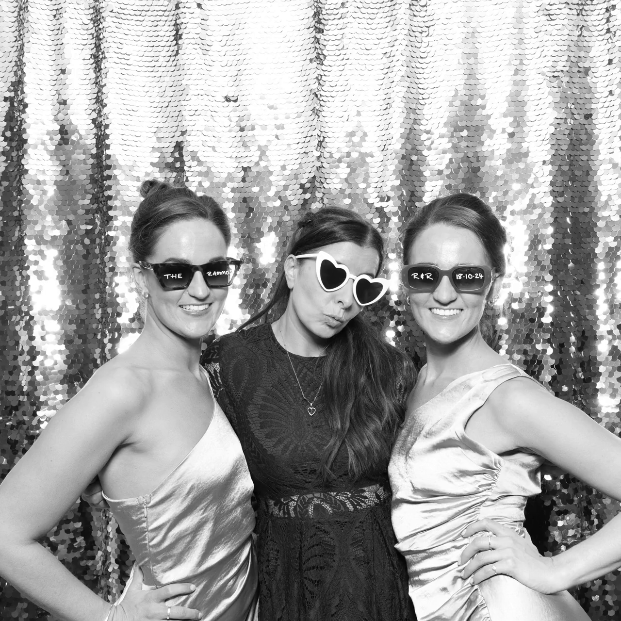 Black and white filter for a print with a group of guests and the bride, posing against a white backdrop, during a wedding party entertainment, for Mad Hat Photo Booth Hyde House