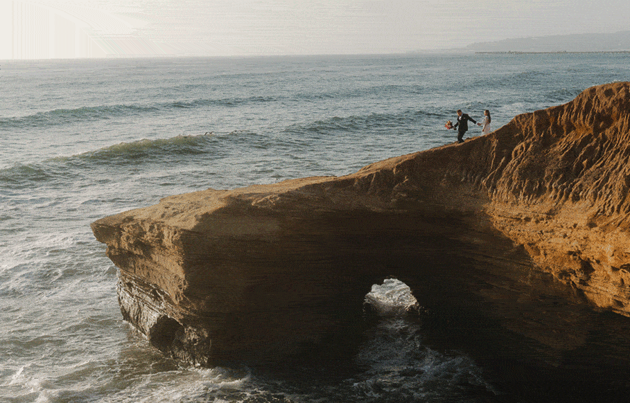 bride and groom on san diego sand cliff with ocean 