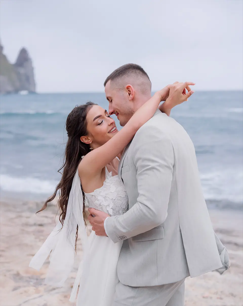 Braut und Bräutigam spazieren vor gelb-weißer Villa, lächelnd Arm in Arm mit Bouquet; reportagefotografie hochzeit und natürliche hochzeitsfotografie prägen den Moment