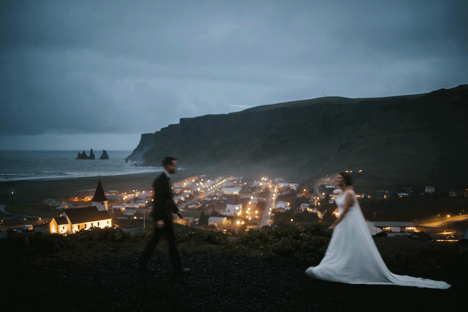 Newlyweds embrace on a rocky cliff overlooking Iceland’s surreal landscape.
