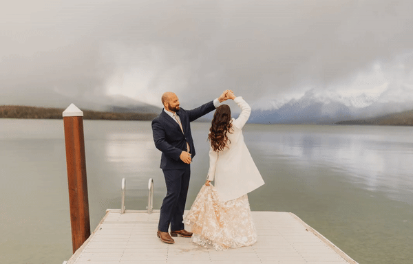 Animated GIF of groom spinning bride on a dock with water and mountains in the background during their Montana elopement.