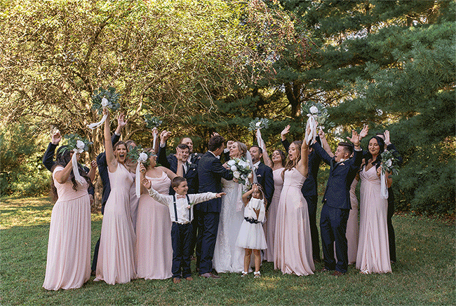 GIF of wedding party in navy and blush celebrating as couple kisses