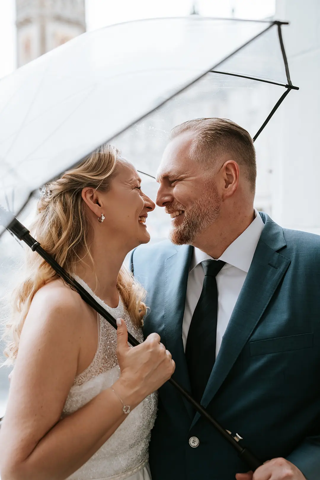 Hochzeitsfotos Hamburg – Nahaufnahme vom Brautpaar unter dem Regenschirm vor dem Rathaus.