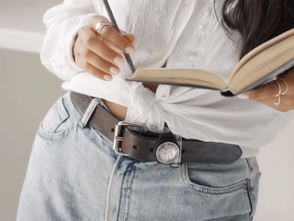 Featured image of a woman holding a notebook and pencil while flipping the pages for Ketch about page copywriting.