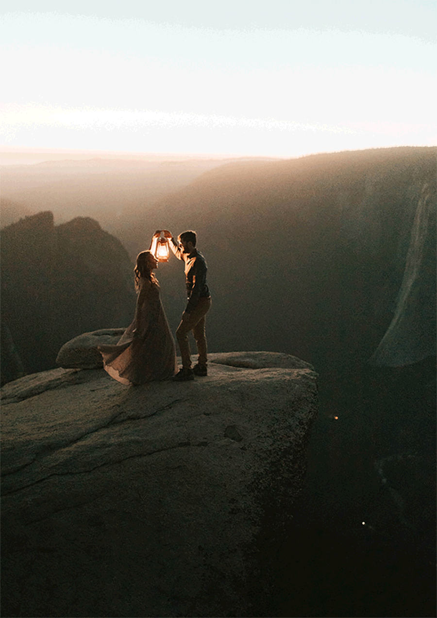 man holding lantern while spinning woman  on mountaintop