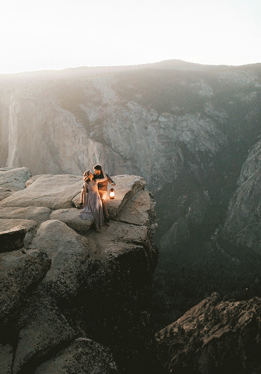 couple embracing on mountaintop while holding lantern