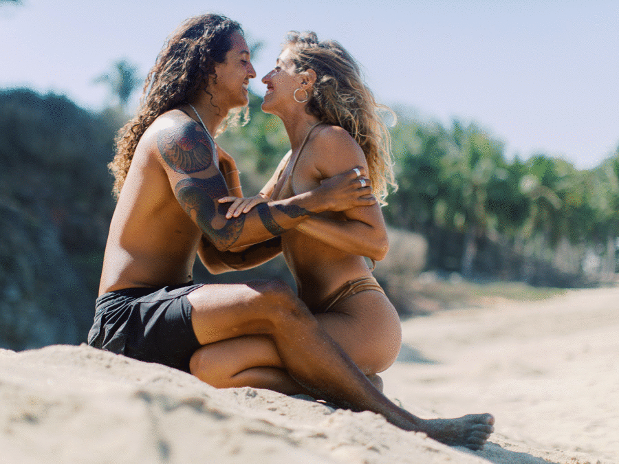 GIF of a couple playfully kissing on a beach wearing a custom gold swimsuit and black swim trunks with tribal snake tattoo by Mexico wedding Photographer J.J. Au'Clair